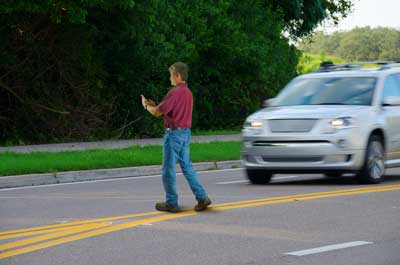 Man crossing in the street in front of a moving vehicle
