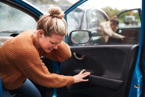 A woman getting out of her car after an accident.